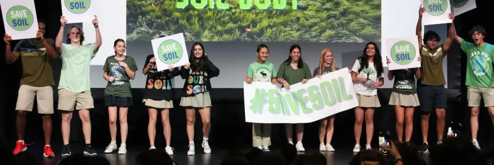 Students on stage with a Save Soil banner